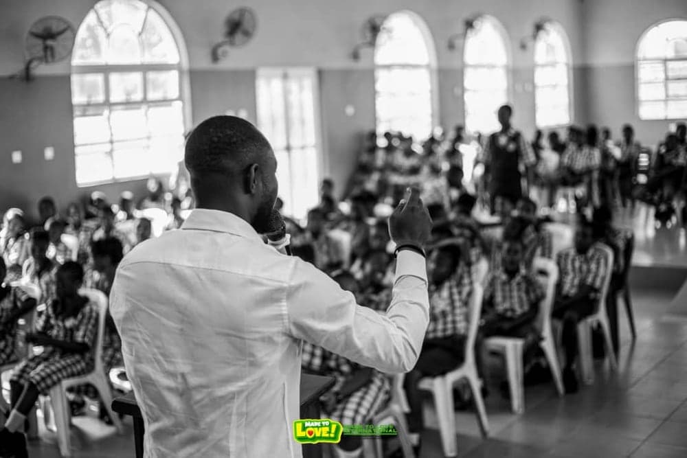 A Love & Light Foundation volunteer addressing rows of secondary school students in a school hall